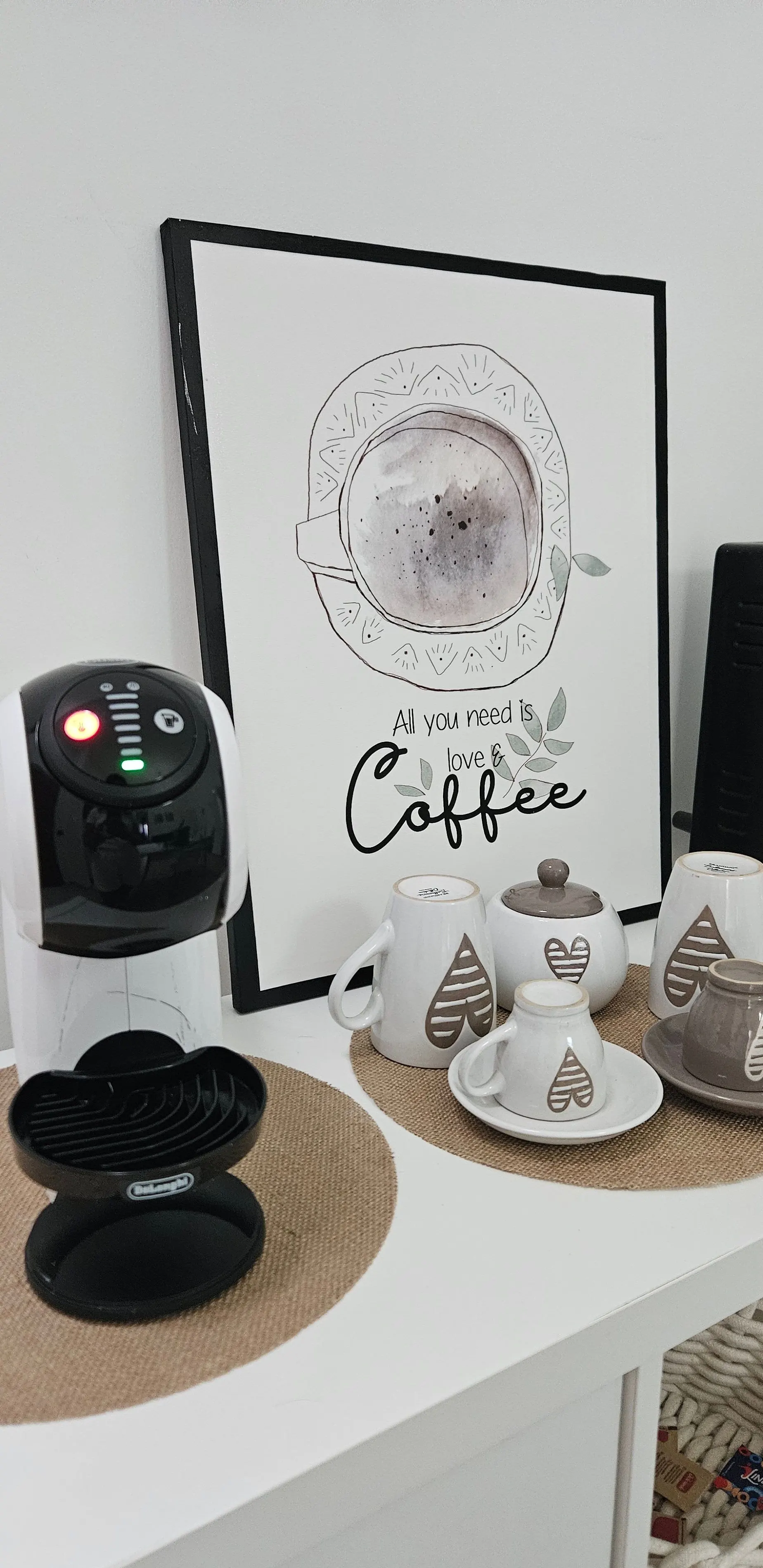 Machine à café à capsules avec tasses et une affiche décorative « Coffee ».
