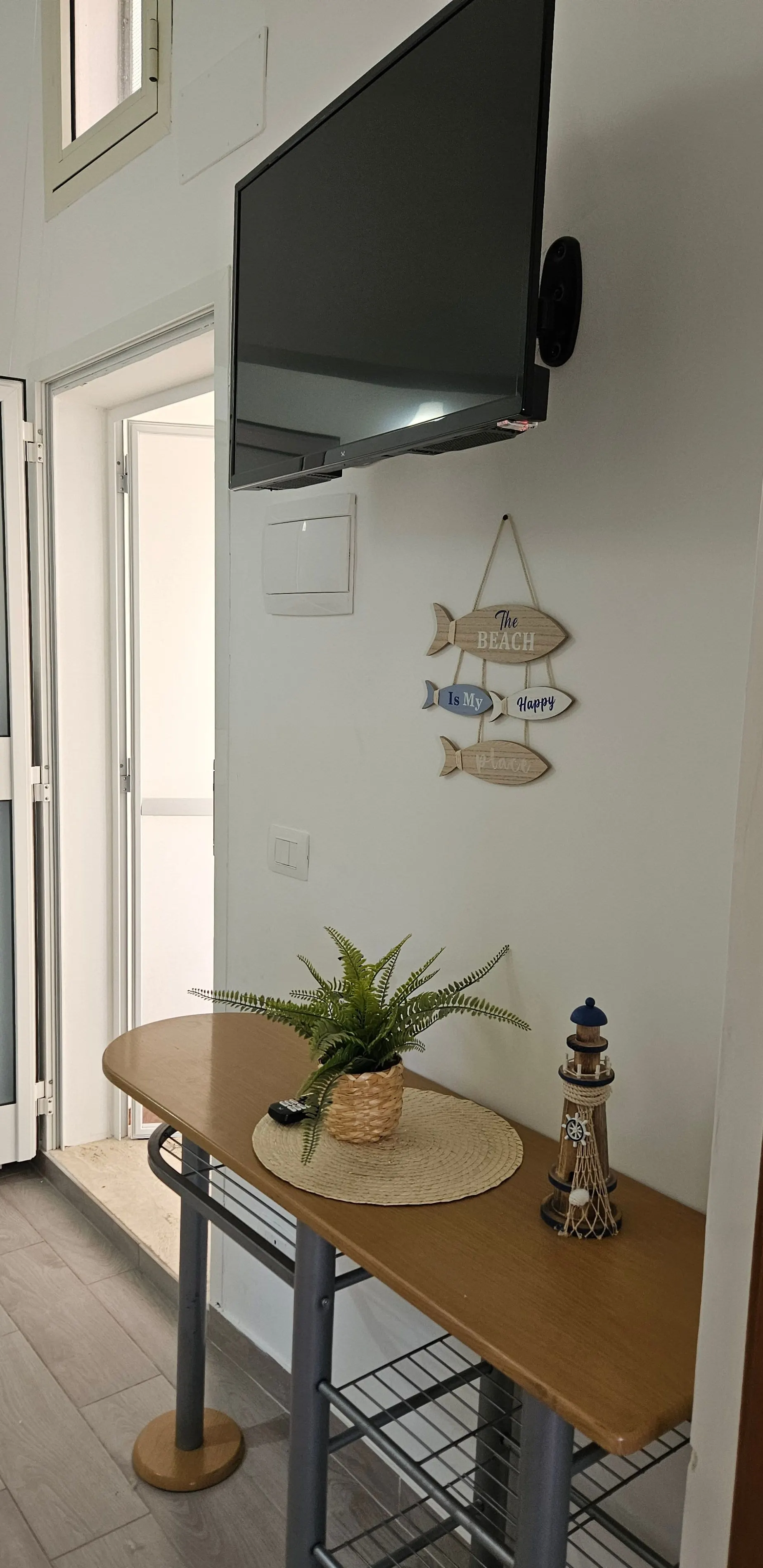 Détails marins : poissons décoratifs au mur et petite plante sur un set de table en corde.